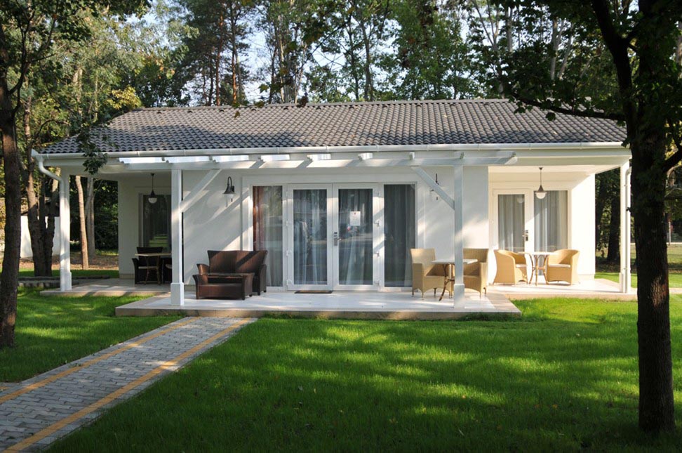 Vario 85 ház: fehér homlokzat, fedett pergolás terasz kerti bútorokkal, cserépfedés